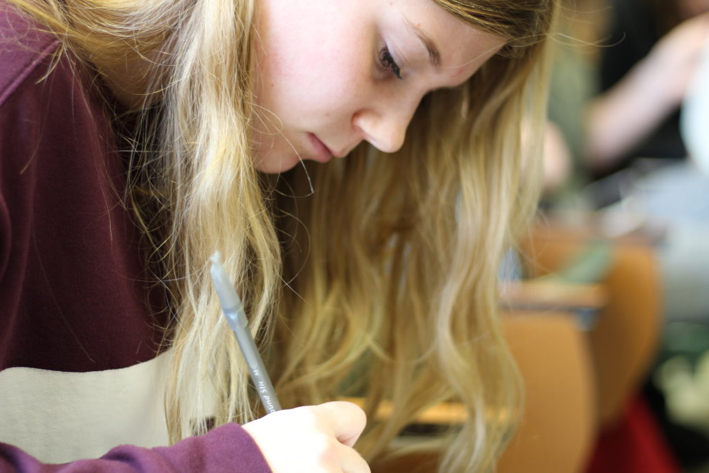 student studying, desk, classroom, writing, football